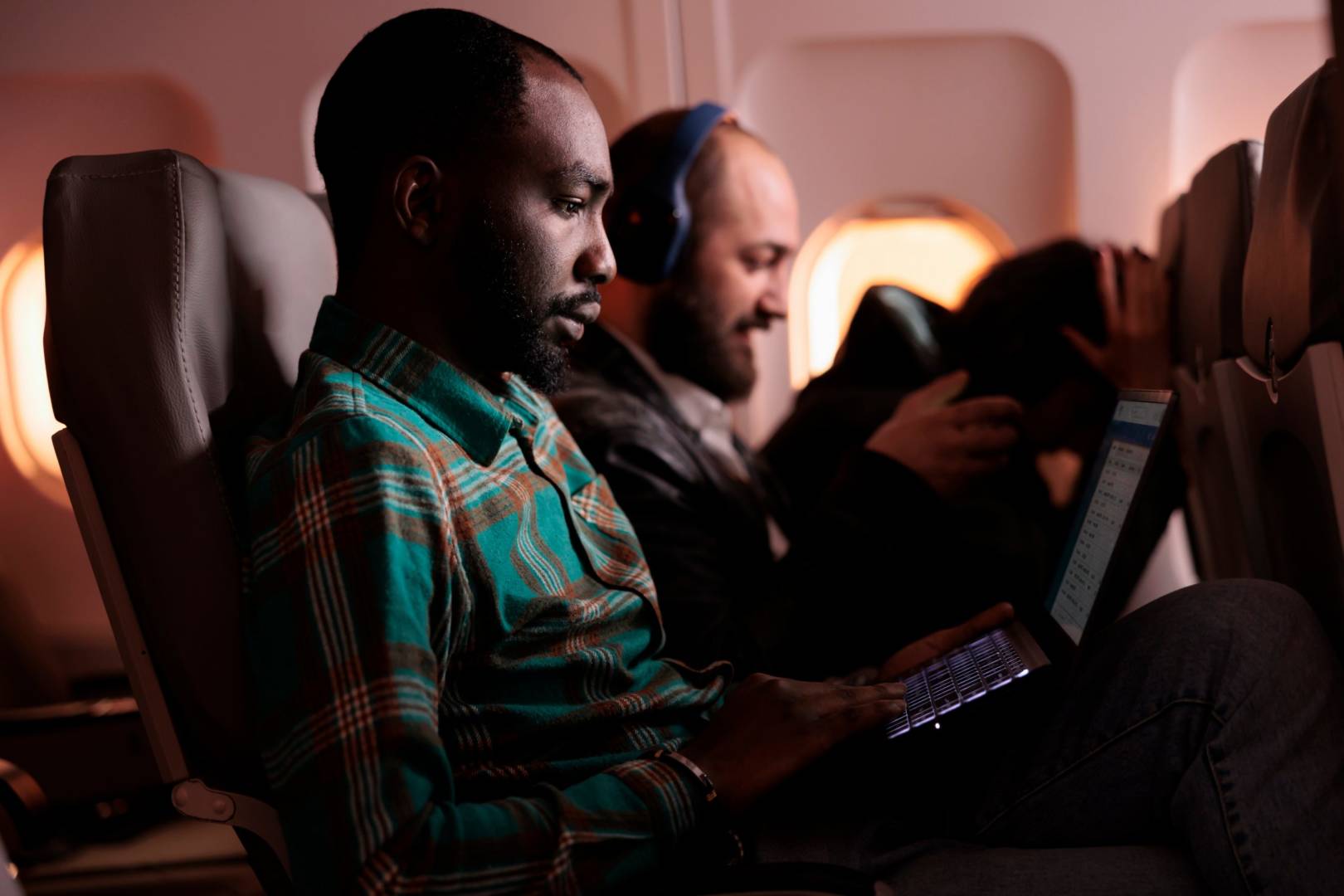 Male employee travelling in economy class and using laptop